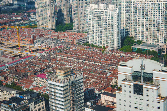 The image depicts Shanghai's urban landscape, contrasting traditional shikumen houses with modern skyscrapers. A crane signals ongoing development.
