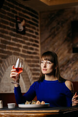 Woman enjoying sushi with wine in a stylish restaurant, creating a refined dining experience