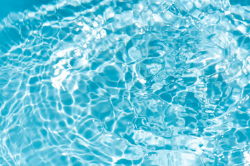 Blue water with ripples on the surface. Defocus blurred transparent blue colored clear calm water surface texture with splashes and bubbles. Water waves with shining pattern texture background.