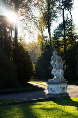 Sonnenstrahlen hinter Skulptur im herbstlichen Schlosspark