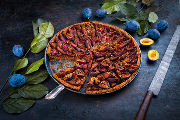 Traditional German zwetschgenkuchen with sliced plums served as close-up on in a backing sheet