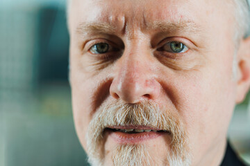 An old bearded man in a black shirt with a piercing look. Close-up portrait of a bearded businessman.