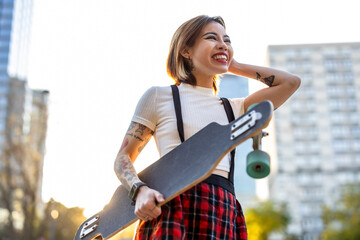 Portrait of a smiling young woman with skateboard in the city
