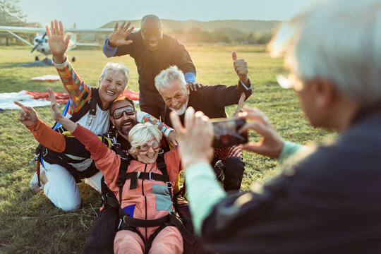 Diverse senior friends taking group photo after skydiving