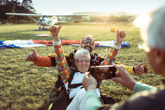 Senior woman celebrating after tandem skydiving with instructor