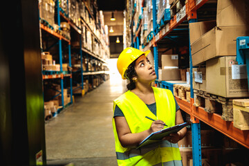 Female warehouse worker inspecting inventory and taking notes