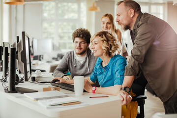 Young people using a computer while working in a startup company office