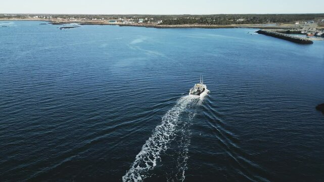Aerial view of commercial lobster fishing vessel as it approaches the breakwater of picturesque Lockeport harbour, Nova Scotia, Canada.  MAX QUAL PRORES422HQ Transcode of 4K H.265 D-CINELIKE capture.