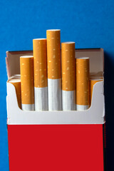 close up  of an opened packet with filtered cigarettes on blue background. selectine focus