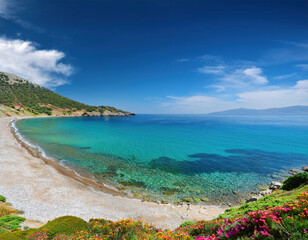 A stunning curved beach with crystal-clear turquoise waters meets rugged coastal cliffs under a bright blue sky in Aegean, Turkey