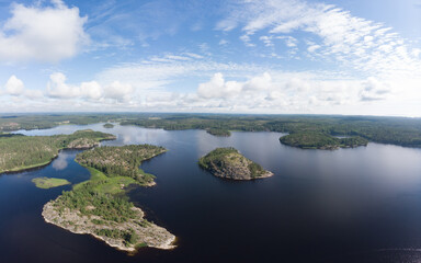 Aerial top view to island Kilpola overgrown with sparse trees in summer sunny day. Skerries Ladoga lake consisting of 650 rocky islands and steep cliffs. National park, Karelia, Russian nature.