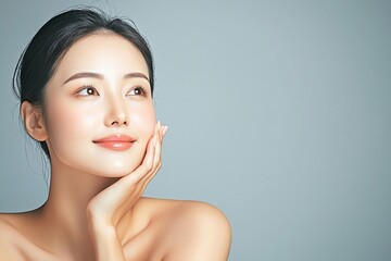 Woman with serene expression against gray background.