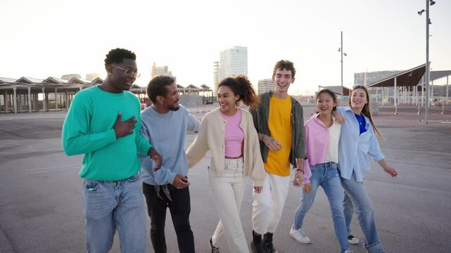 Group of young diverse friends walking relaxed and talking to each other and sharing a fun leisure time enjoying friendship together in city. Generation z youth community and people union