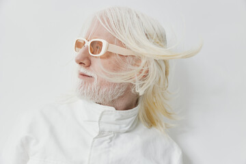 Stylish elderly man with long white hair, wearing trendy sunglasses and a white jacket against a...