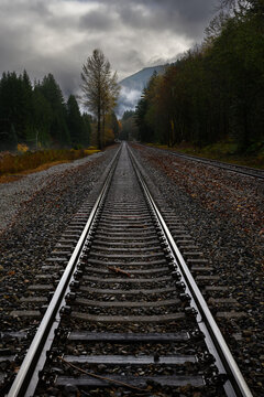 Moody wet day with cloudy sky at straight railroad track converging in distance