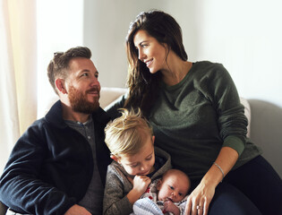 Obraz premium Happy, bonding and parents with children in home with love, care and newborn baby for family. Smile, relax and kids on sofa with mother and father in living room for rest and connection at house.