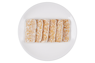 Slices of raw tempeh on a white plate isolated transparent