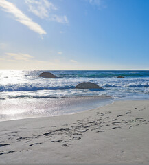Sand, beach and ocean coast for holiday, travel or vacation in nature with blue sky outdoor. Sea water, stones and waves in horizon with land for tourism, island or rocks with mockup space in Greece