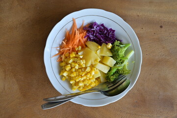 Delicious vegetable salad with chicken egg and corn. Healthy food. Flay lay view on wooden table