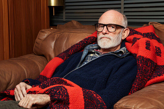 a fevered elderly man wrapped in thermal blanket, symptomatic expression, recovering from a cold