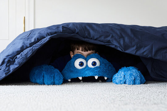 child discovering friendly blue monster under bed