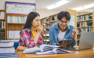 Students are consulting each other working on laptops and searching for books to study, make reports, find useful information in university room. Concept of reading, learning and intelligence.