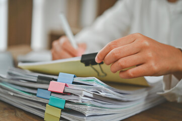 A person is writing on a stack of papers with a pen