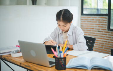 Young Asian college student doing report, drawing on tablet in cafe. Communicating and researching online.