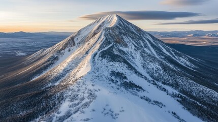 Majestic Snow-Capped Mountain Peak Surrounded by Lush Forests and Expansive Wilderness Under a Soft Golden Sunset Sky in a Tranquil Natural Landscape