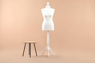 Female mannequin and stool on beige background