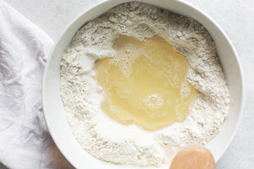 Overhead view of challah dough being mixed, top view of homemade challah dough being mixed in a white bowl, process of making challah
