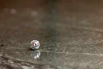A small disco ball on a stone table. Club concept. New Year decoration