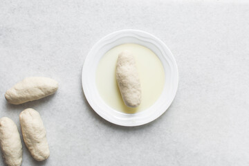 Overhead view of noodles dough in oil in a white plate, top view of homemade biang biang noodles in oil, process of making hand pulled noodles