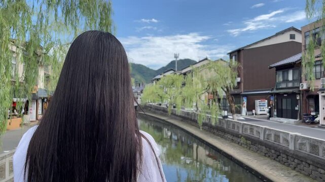 城崎温泉街の橋の上から街並みを臨む女性の後ろ姿	