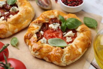 Tasty galettes with tomato, basil and cheese on white wooden table, closeup
