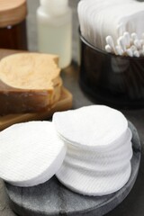 Many cotton pads and other toiletries on grey table