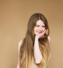 Happy young woman smiling sincerely on beige background.