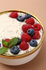 Tasty cooked semolina porridge with berries and mint on pale brown background, closeup