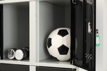 Open lockers with dumbbells and soccer ball, closeup