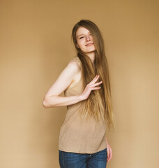 Happy young woman smiling sincerely on beige background.