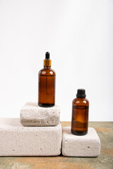 Amber Glass Bottles with Dropper and Screw Cap on Stone Blocks and Fabric Accent