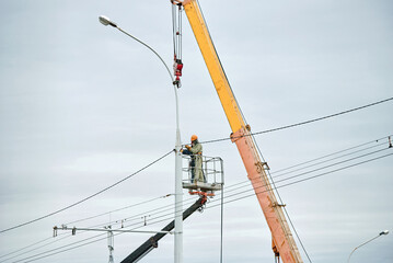 Streetlight repair with welding crew on crane platform. Workers on crane platform welding street...