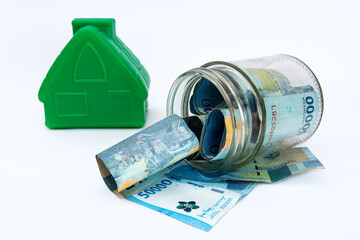 fifty thousand rupiahs dropped in a clear jar. a picture of savings to buy a house