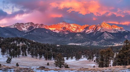 A vibrant, colorful sunset paints the sky above a snow-covered mountain range.