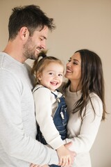 Fototapeta premium Joyful Family Portrait Featuring Loving Parents and Smiling Toddler