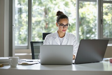 Fototapeta premium Focused Female Scientist Working in Modern Laboratory Setting with Laptops