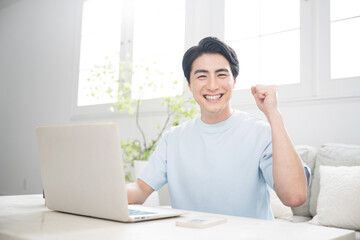 Smiling young man using a computer in a brightly lit room. Fresh camera gazes and guts of freelancers, engineers, designers, and other professionals.