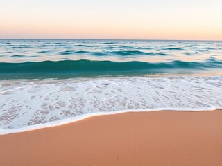 Obraz premium A soft blue ocean wave breaks on the shore of a tranquil fine sandy beach at sunset, creating a beautiful and serene scene, gentle movement, evening light, coastal scenery