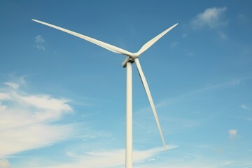 Dynamic angle shot of wind turbine, green energy concept, against blue sky