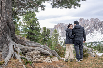 Couple under the tree enjoy the view of alpine mountain landscape snowy.